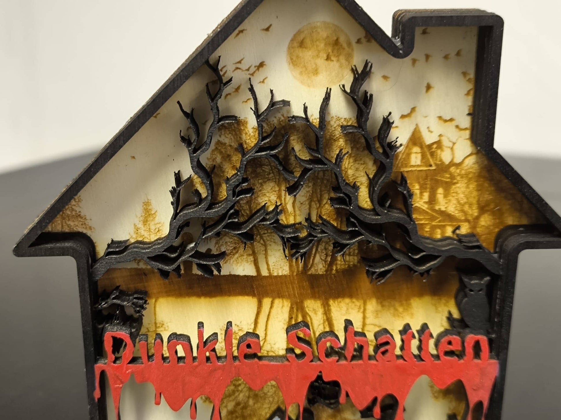 3D Holzdeko Gruselhaus mit gruseligen Bäumen und blutrotem Schriftzug Dunkle Schatten