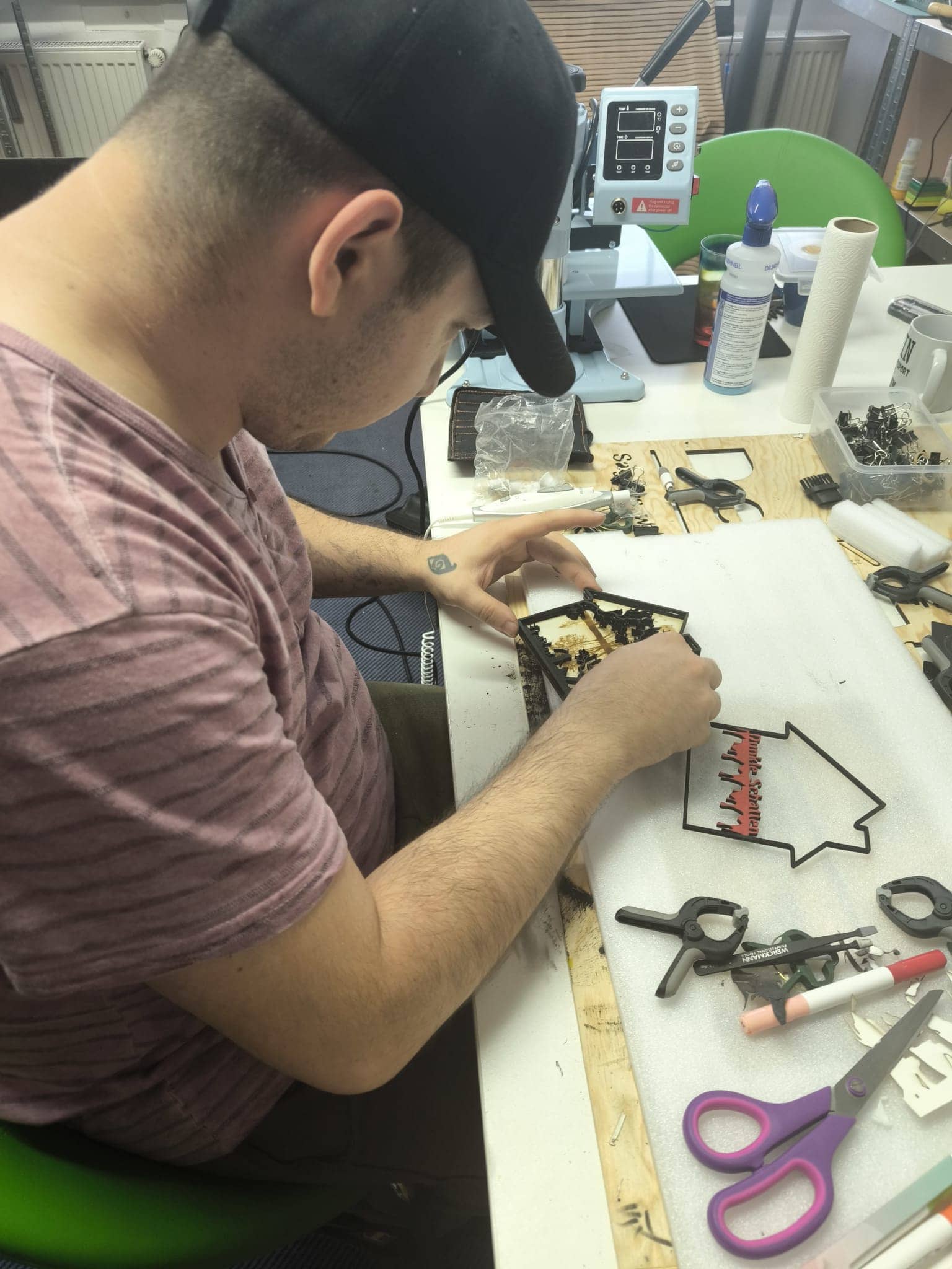 Ein Handwerker erstellt eine 3D Holzdeko Gruselhaus mit Werkzeugen auf einem Tisch in einem kreativen Umfeld