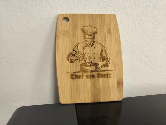 Graviertes Schneidebrett personalisiert mit Kochmotiv und dem Text Chef am Brett